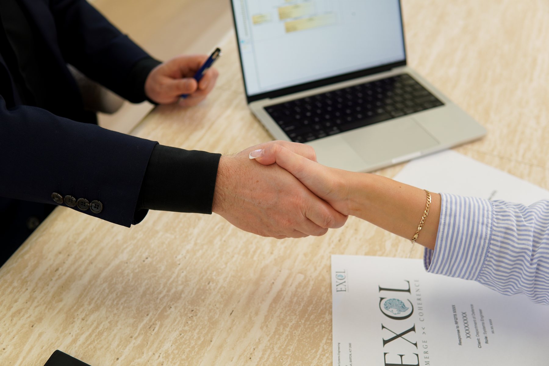 EXCL consultant shaking hands with a client over EXCL documents
